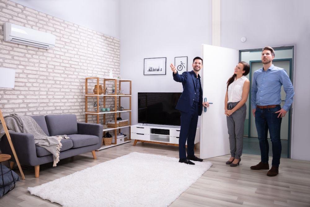 Propriétaire faisant visiter un salon lumineux à un couple de candidats locataires